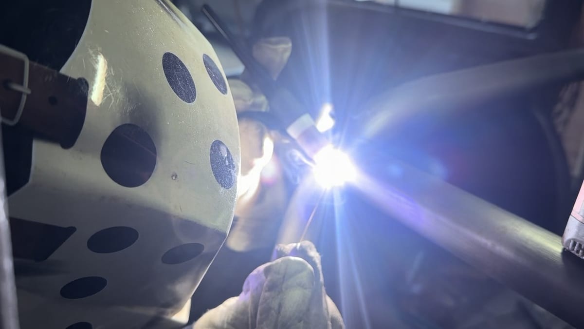 Welding a roll cage joint, arc lit under a helmet