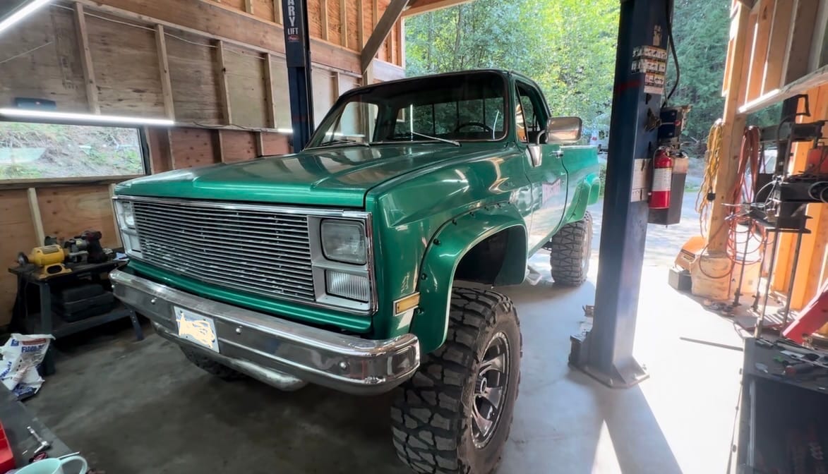 A green Chevrolet pickup up on the lift in the shop